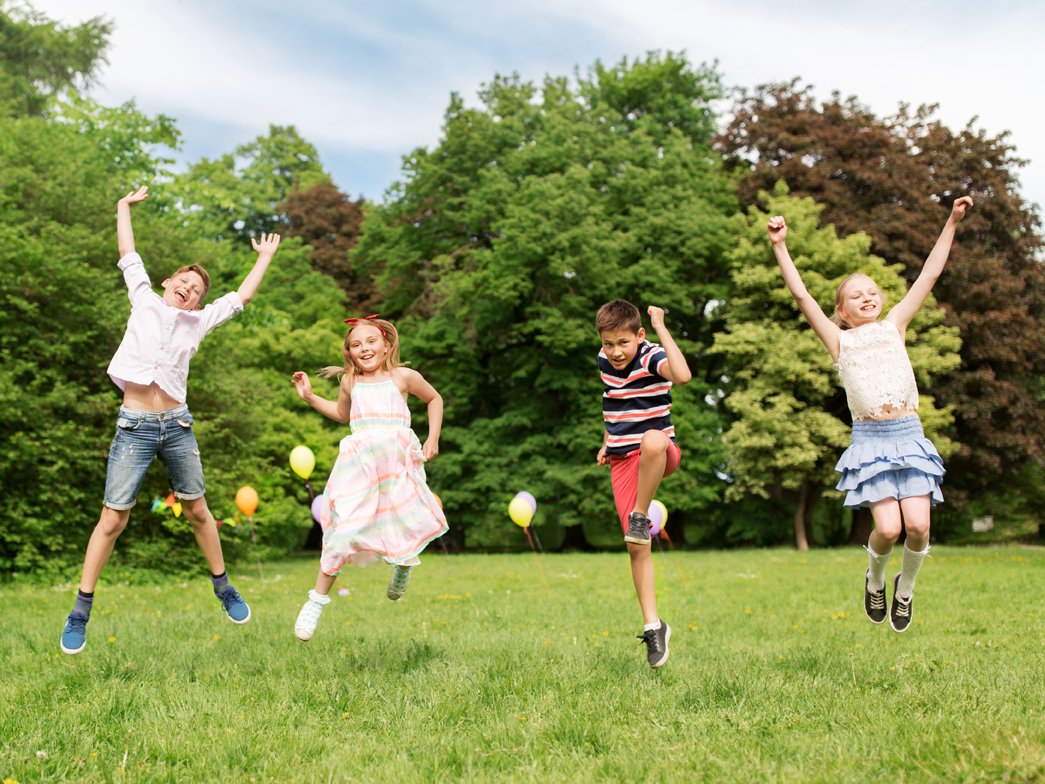 Kinder springen auf Wiese