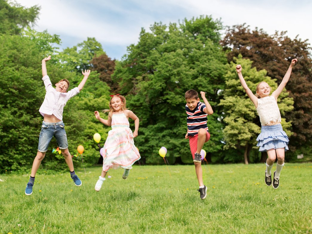 Kinder springen gemeinsam auf Wiese